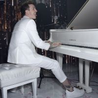 Ілон Маск в білому костюмі за білим роялем